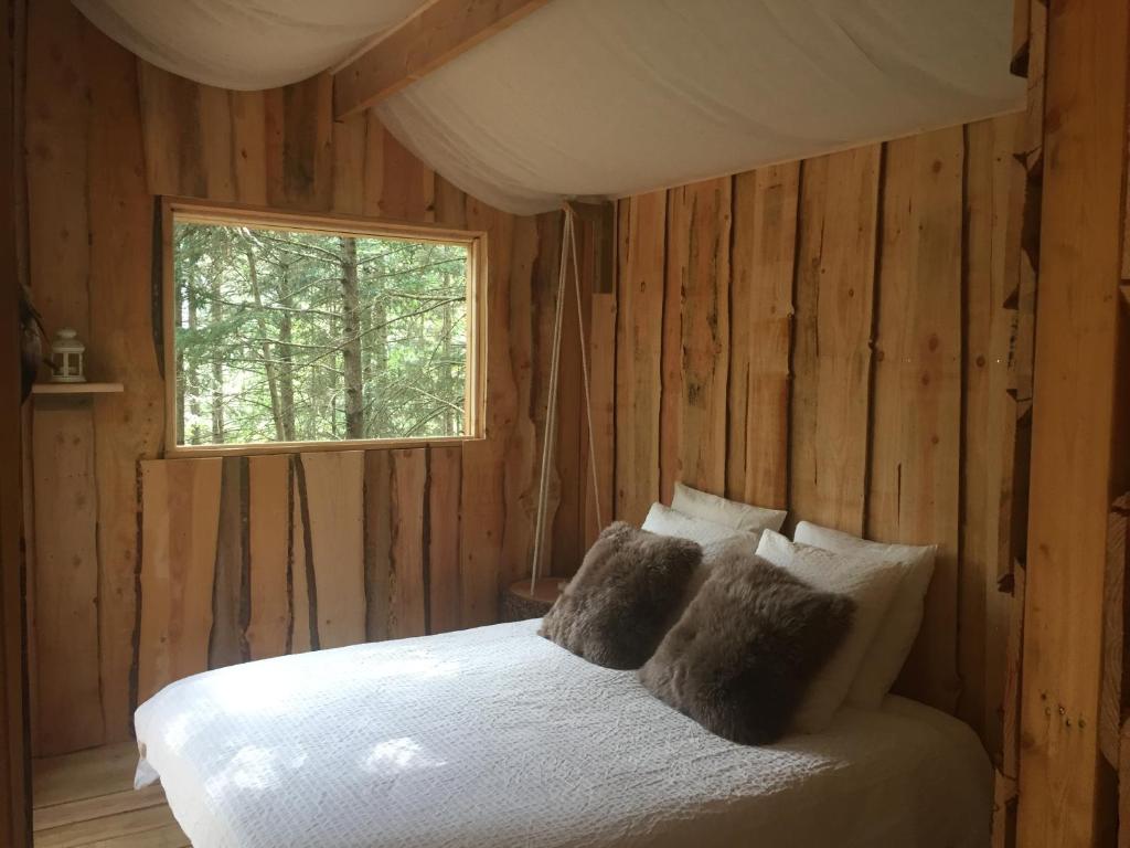 1 dormitorio con 1 cama blanca y ventana en cabane de l'Ecureuil, en Châtel-Guyon