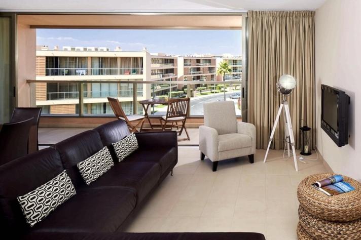 uma sala de estar com um sofá preto e uma televisão em Apartamento T2 Herdade dos Salgados em Albufeira