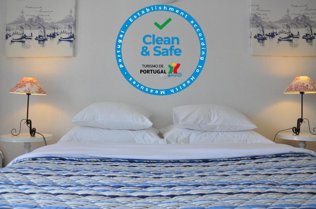 a sign that says clean and safe above a bed at Mil Reis in Vila Nova de Milfontes