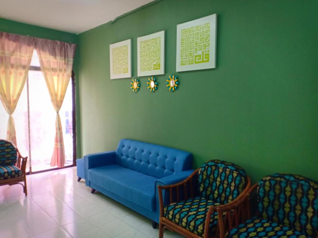 a waiting room with a blue couch and two chairs at Adiana Homestay in Kuah