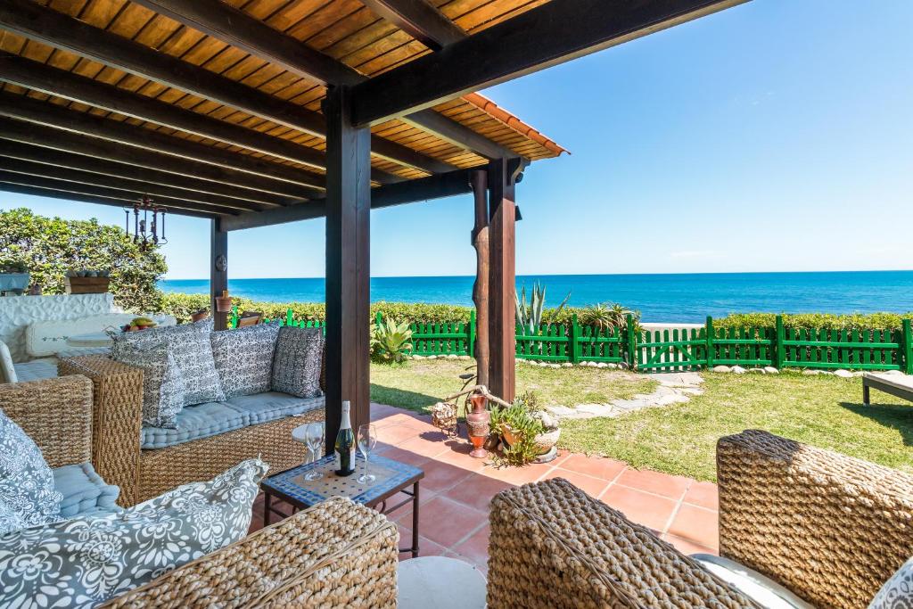 eine Terrasse mit einem Sofa, Stühlen und Meerblick in der Unterkunft Beach Villa Dorada in Estepona