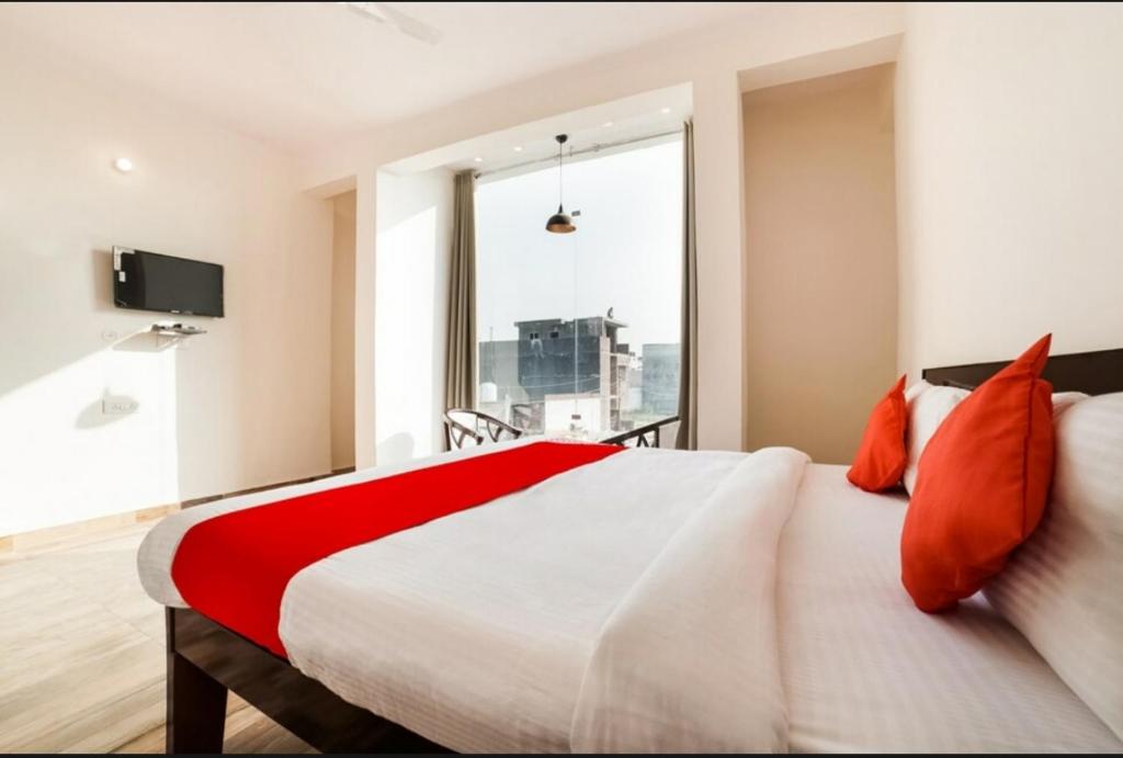1 dormitorio con 1 cama grande con almohadas rojas en Hotel Arrow 19, en Bareilly