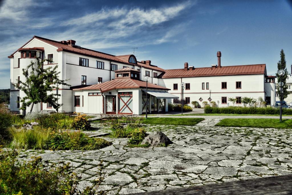un grande edificio bianco con un sentiero in pietra davanti di Hotell Bogesund a Ulricehamn