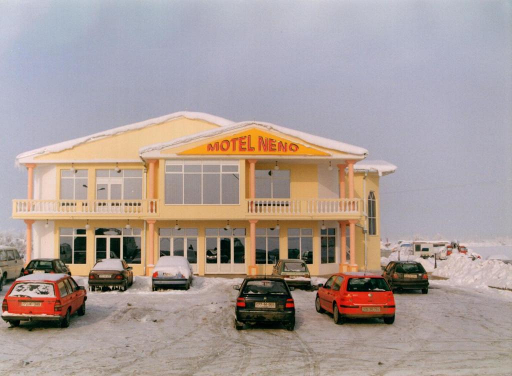 un motel con coches aparcados fuera de él en la nieve en Motel Neno, en Bijeljina