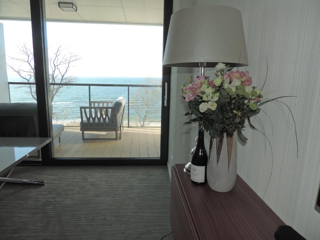 eine Vase aus Blumen auf einem Tisch mit einer Lampe in der Unterkunft Apartament 514 Seaside z widokiem na morze in Kołobrzeg