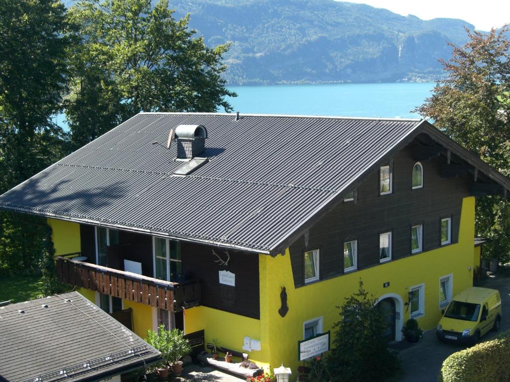 ein gelbes und schwarzes Haus mit einem Auto davor in der Unterkunft Ferienwohnungen Landhaus Gerum in St. Wolfgang