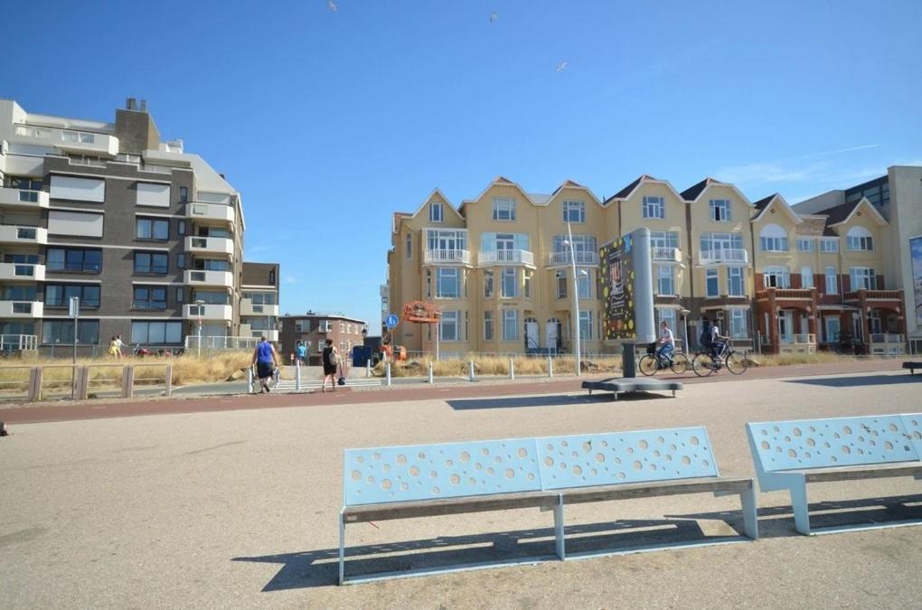two benches sitting in front of a large building at Beach House Rodine - free parking & bikes in Scheveningen