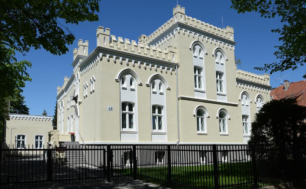 duży budynek z płotem przed nim w obiekcie Rezydencja Myśliwska - Apartamenty w Koszalinie