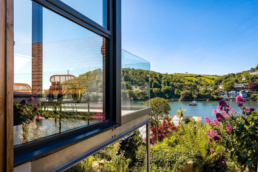 a window with a view of a river and flowers at Two Guns – Contemporary, Stylish Townhouse With Stunning Sea Views in Kingswear