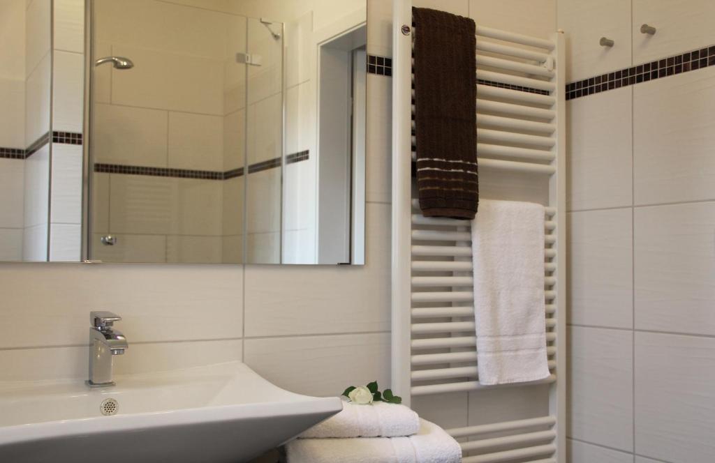 a white bathroom with a sink and a mirror at Hotel & Café Strandeck in Prerow