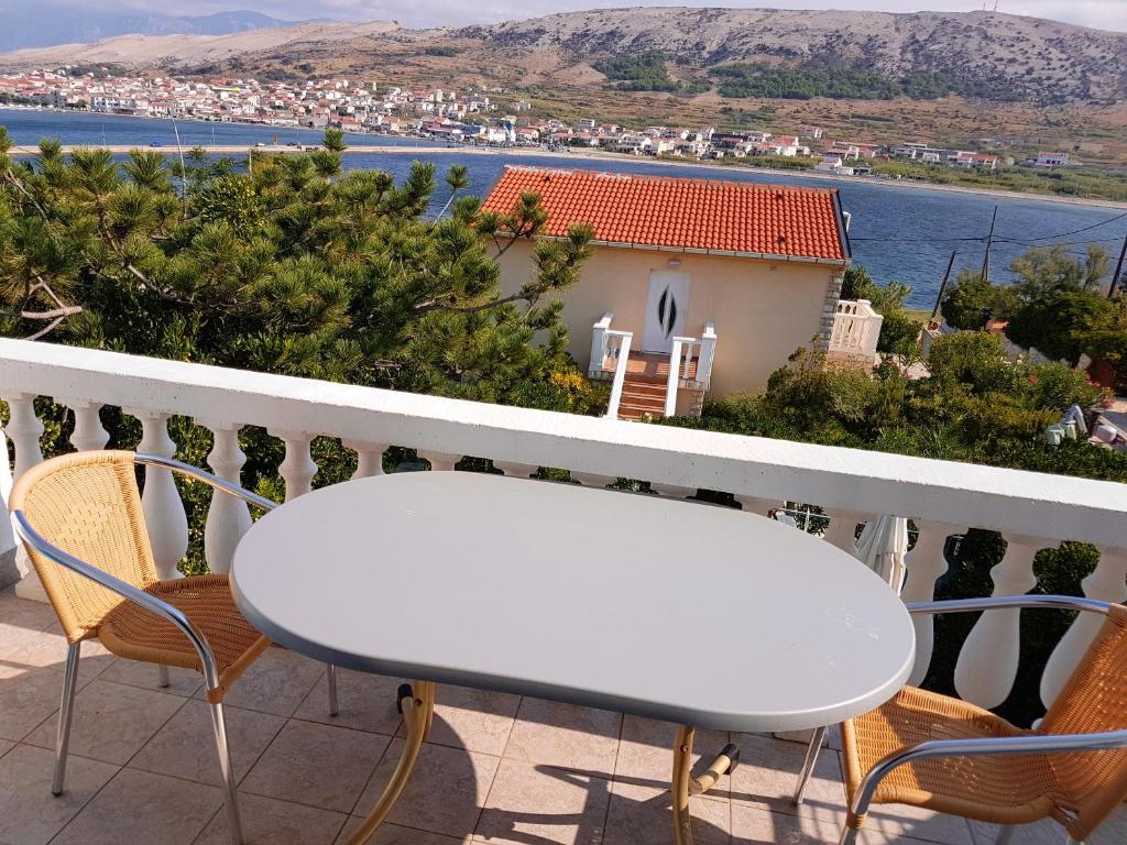 a white table and chairs on a balcony overlooking the water at 2 bedrooms appartement at Pag 100 m away from the beach with sea view enclosed garden and wifi in Pag