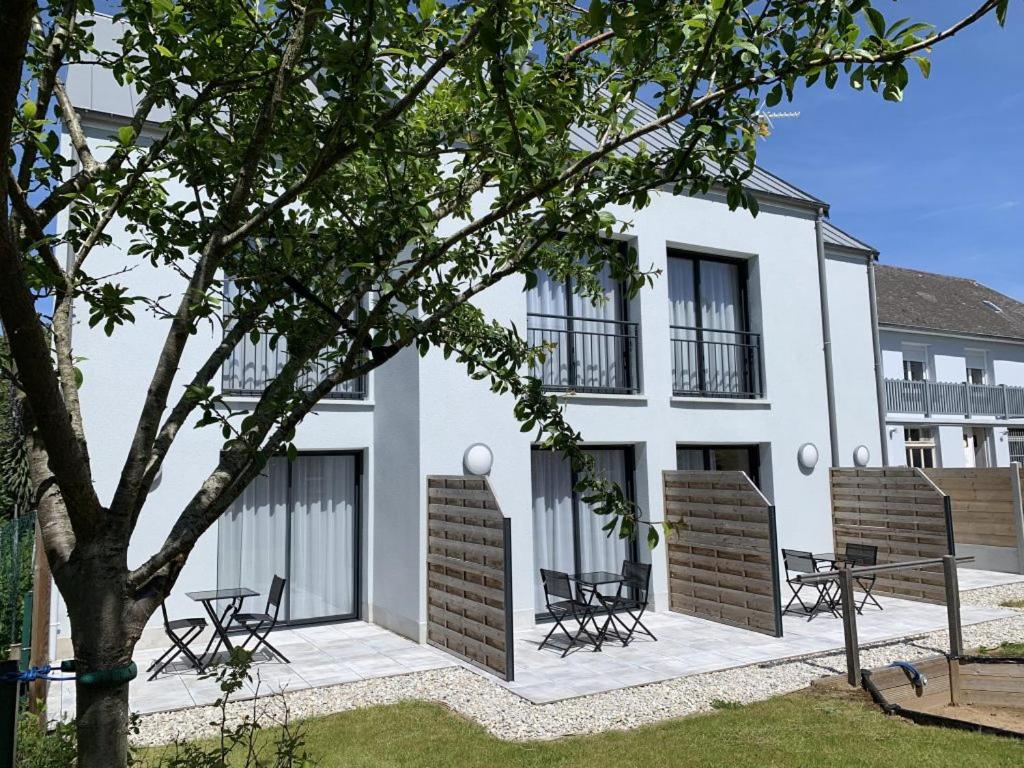 a white building with chairs and a tree in front of it at Hotel au Moyne De Saire in Réville