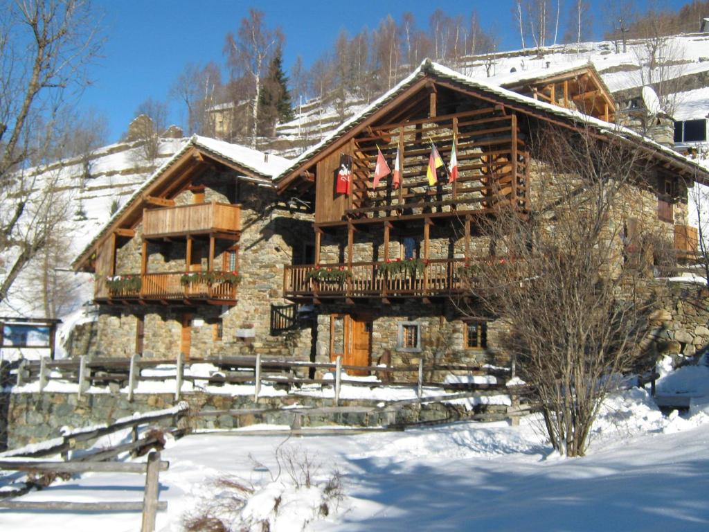 una cabaña de madera en la nieve con dos banderas en L'Etoile Du Berger, en Lillianes