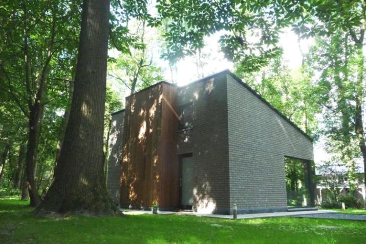 a small brick house with a tree in a park at Vakantiewoning Kokilla in Ieper