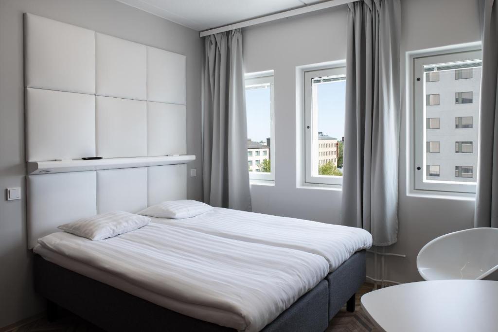 a bedroom with a large bed with a window at Omena Hotel Vaasa Espen in Vaasa