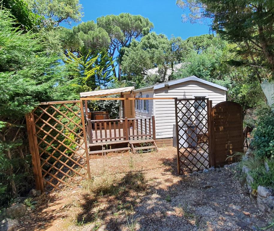 a shed with a gate and a wooden fence at Mobil Home O'HARA Confort Plus Parc Saint James Montana in Gassin