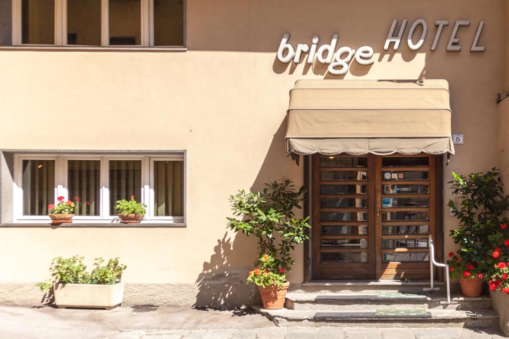 a hotel with potted plants in front of a building at Bridge Hotel in Bagni di Lucca