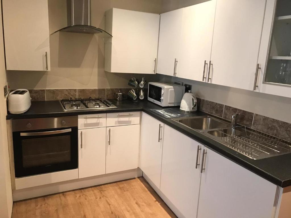 a kitchen with white cabinets and a sink and a microwave at Jrs place in Merthyr Tydfil