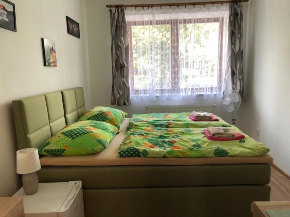 ポジェブラディにあるPenzion Na Hraziの窓とベッドカバーが備わるベッドルームのベッド1台分です。