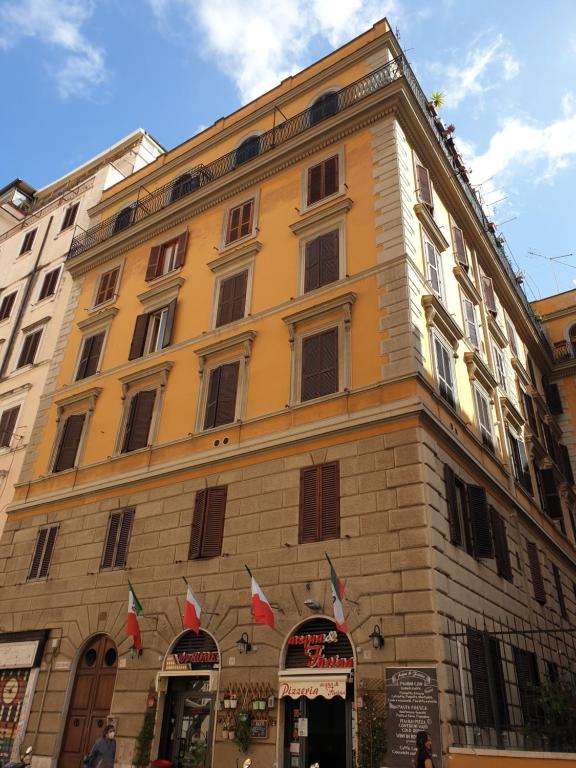um edifício amarelo com bandeiras à frente em Guest House Hello Roma em Roma