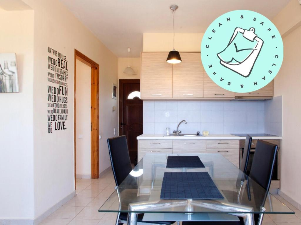 - une cuisine avec une table en verre, des chaises et un évier dans l'établissement Makis Apartments, à Siteía