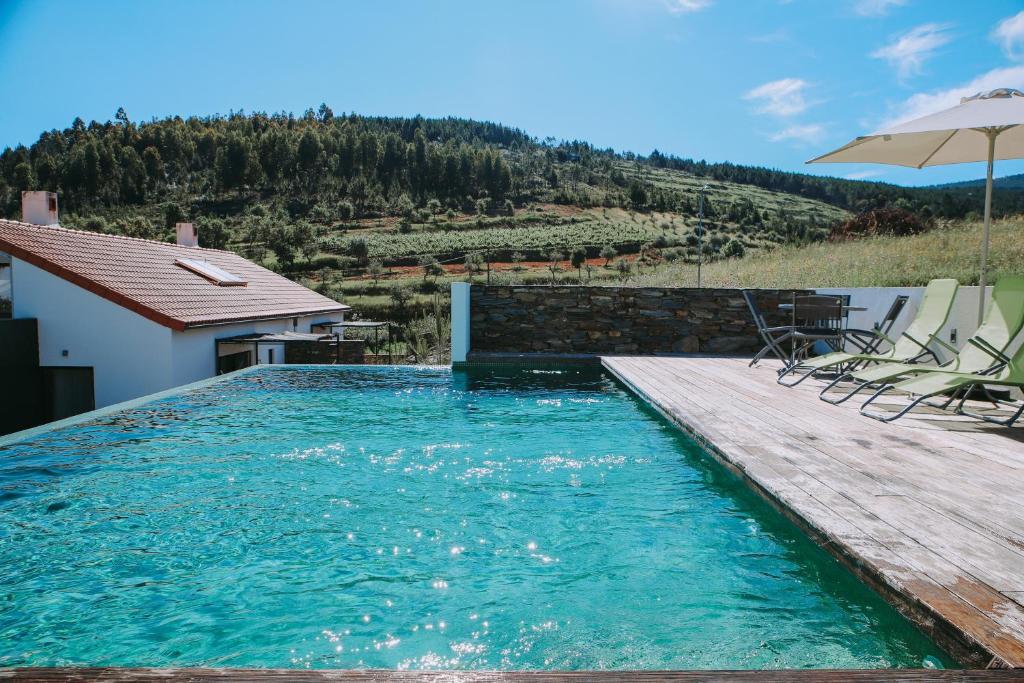 a swimming pool with a wooden deck and an umbrella at Casas da Fontanheira in Marvão