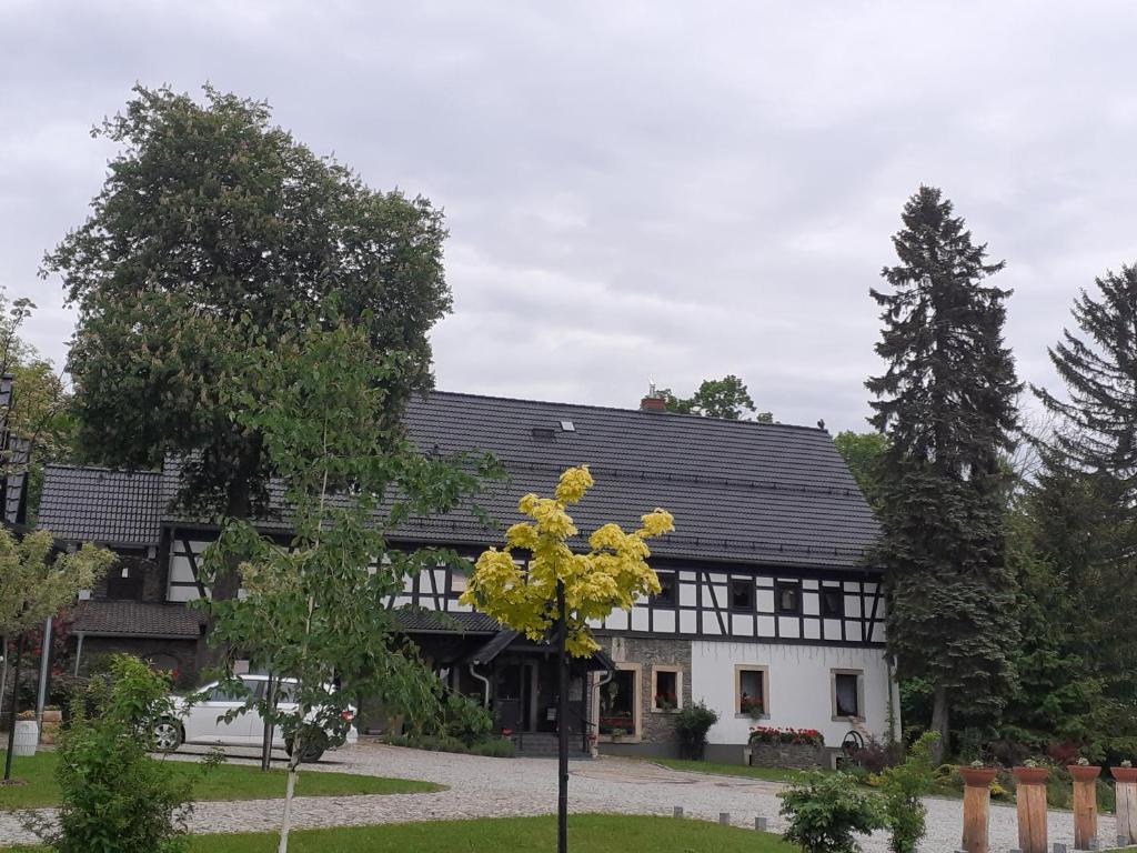 ein Schwarz-Weiß-Haus mit einem Baum davor in der Unterkunft Agroturystyka Łysa Góra in Jelenia Góra