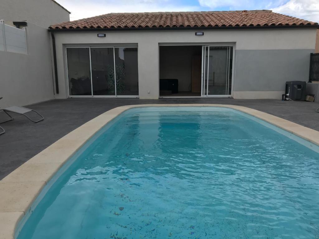 a large blue swimming pool in front of a house at VILLA PINTOURINA in Sallèles-dʼAude
