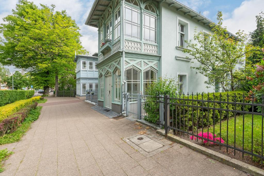 ein weißes Haus mit einem Zaun davor in der Unterkunft Apartament Haffnera 30 in Sopot