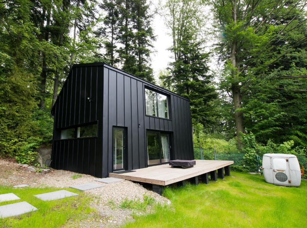 ein schwarzes winziges Haus mit einer Bank im Hof in der Unterkunft Minimal House in Szczyrk