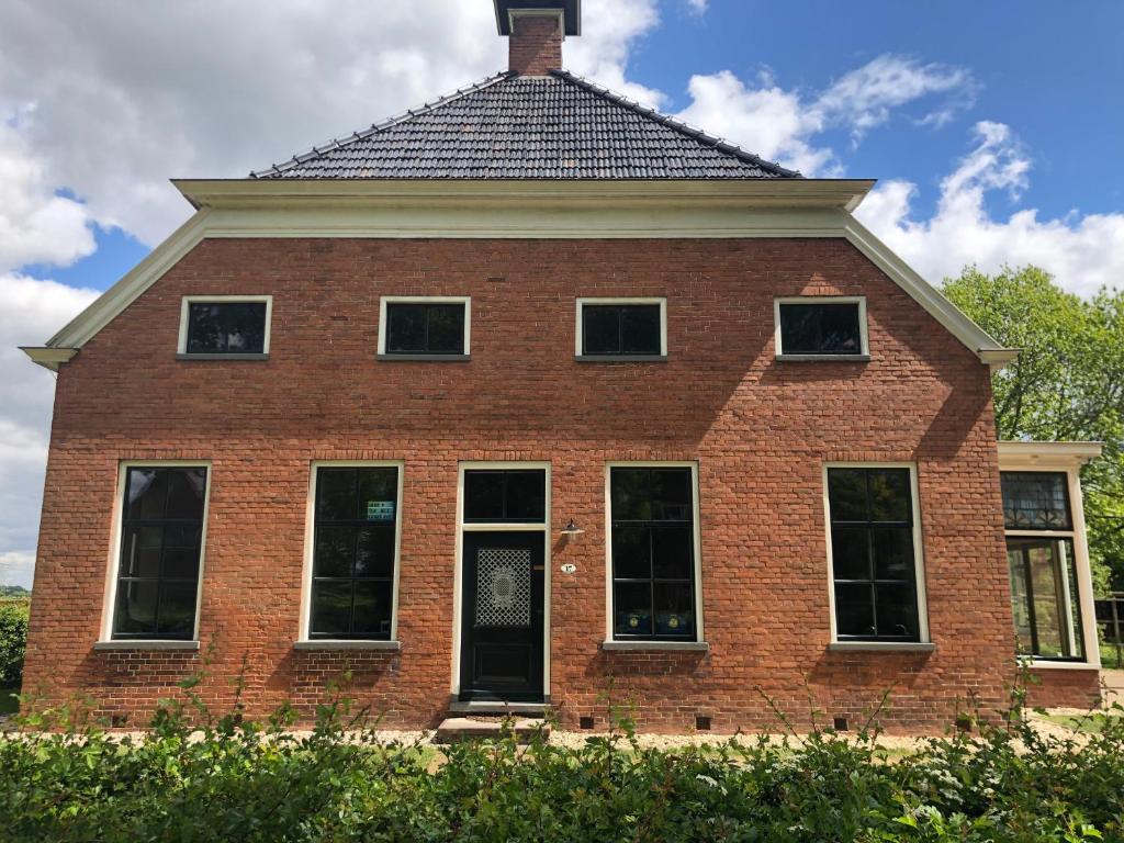 una casa de ladrillo rojo con techo de gambrel en B&B In het Voorhuys, en Zuidlaren