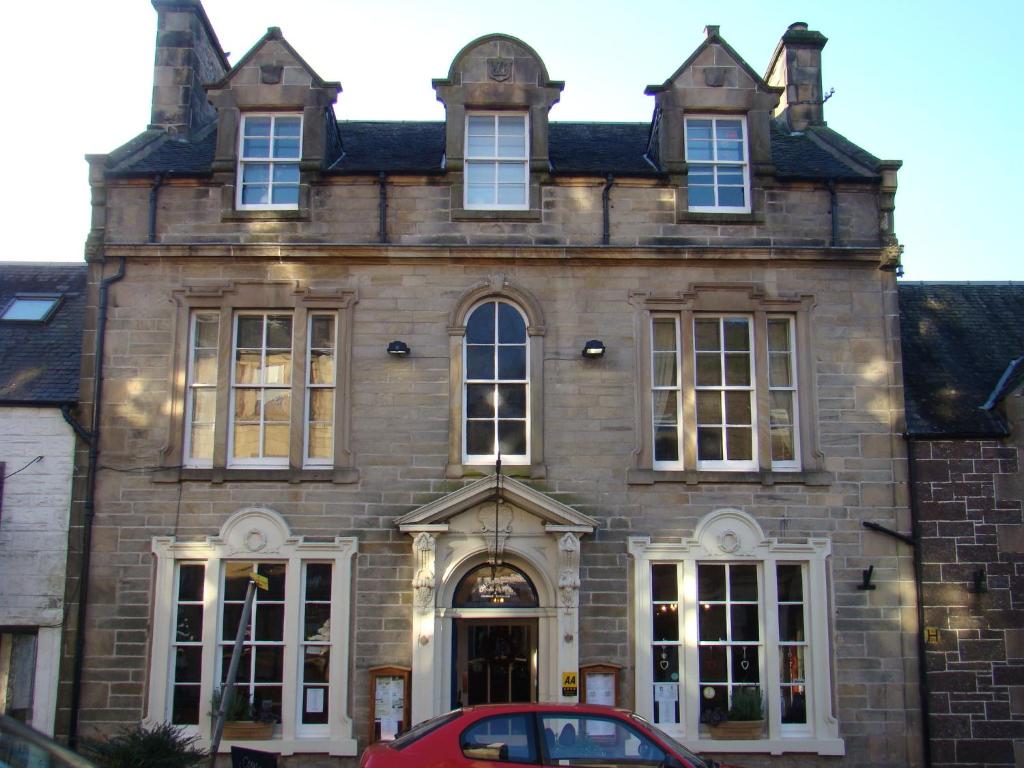 un edificio con un coche rojo estacionado frente a él en Callander Meadows, en Callander