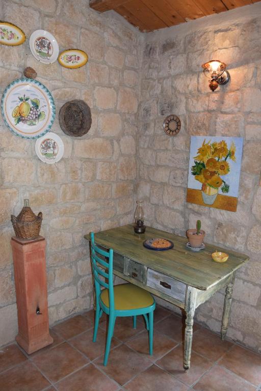 una mesa con una silla y platos en una pared de piedra en Casa il Carrubbo, en Frigintini