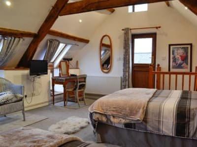 a bedroom with two beds and a desk in a room at The Granary in Swansea