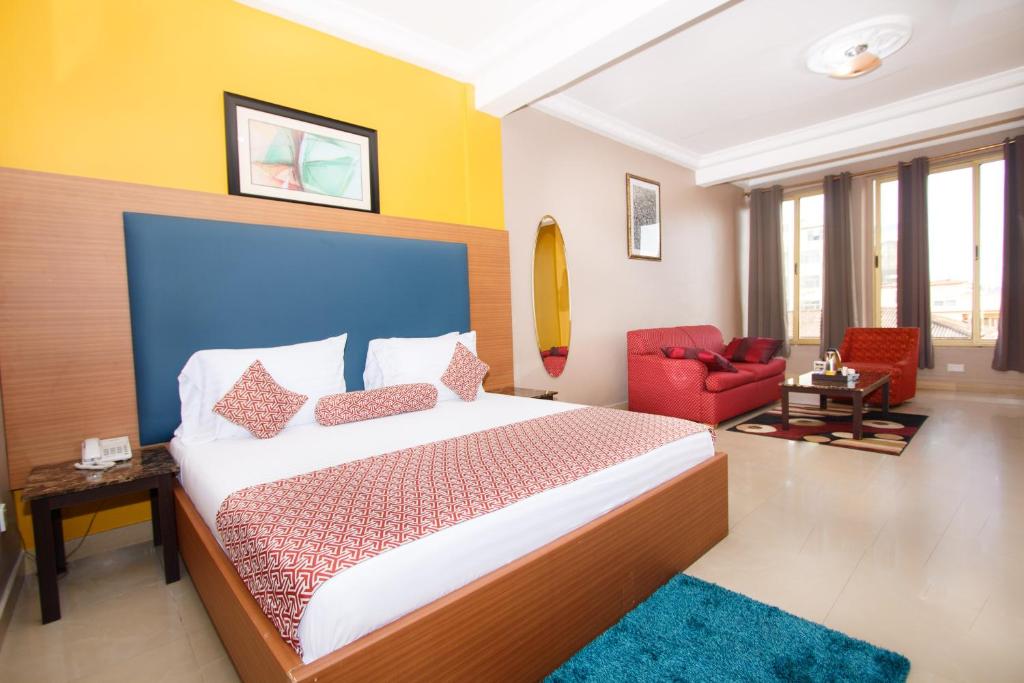 a bedroom with a large bed and a red chair at Prestige Suites in Accra