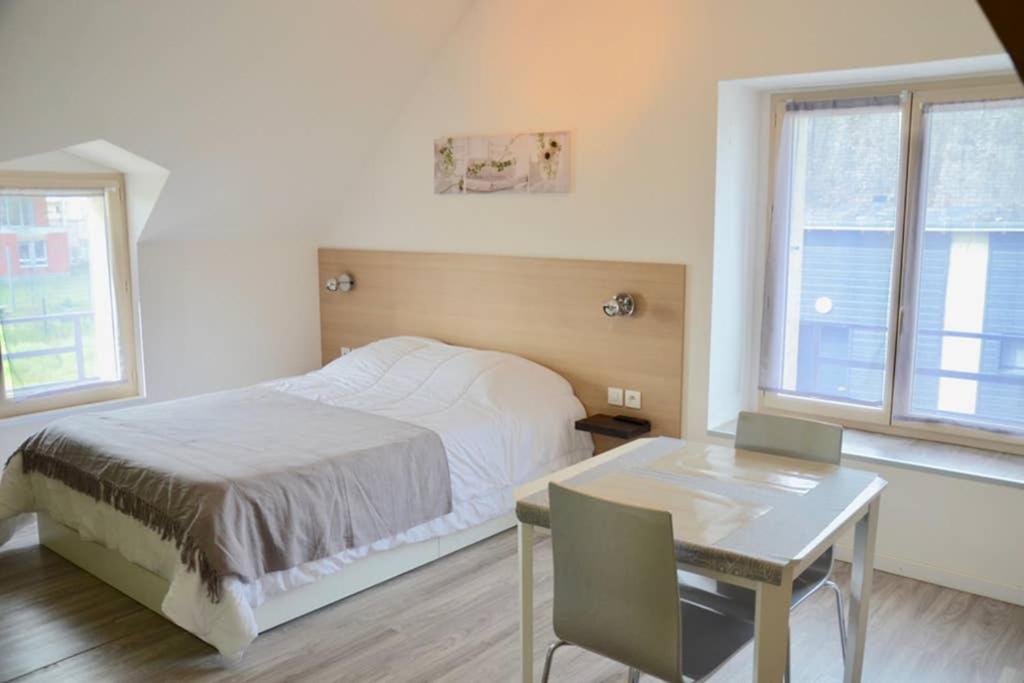 sypialnia z łóżkiem, stołem i oknami w obiekcie La petite maison appartement 2 w mieście Avoine