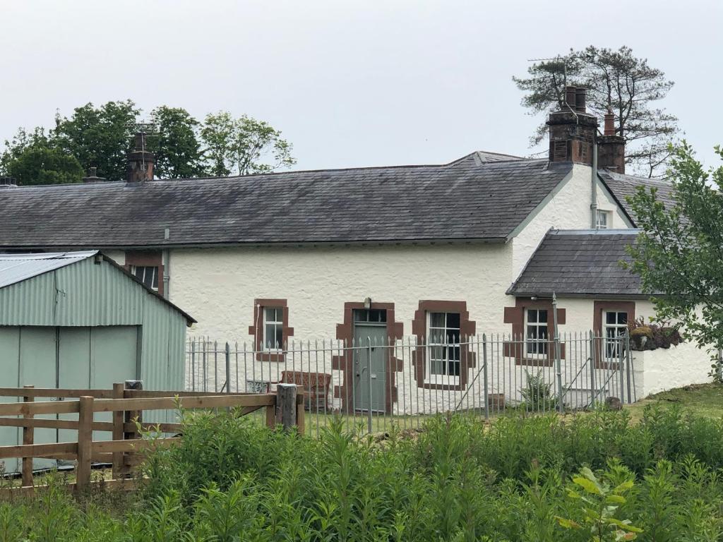 a white house with a fence in front of it at Laundry Cottage in Dumfries