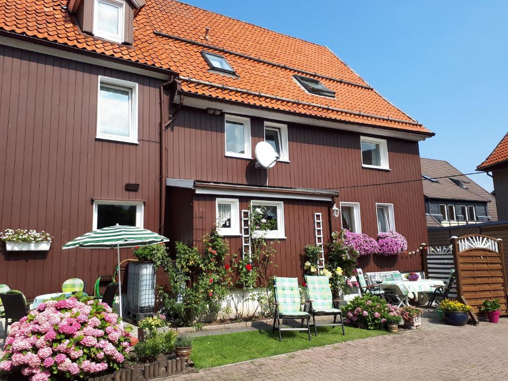 ein Haus mit Stühlen und einem Sonnenschirm davor in der Unterkunft Gästehaus Andrea in Hahnenklee-Bockswiese