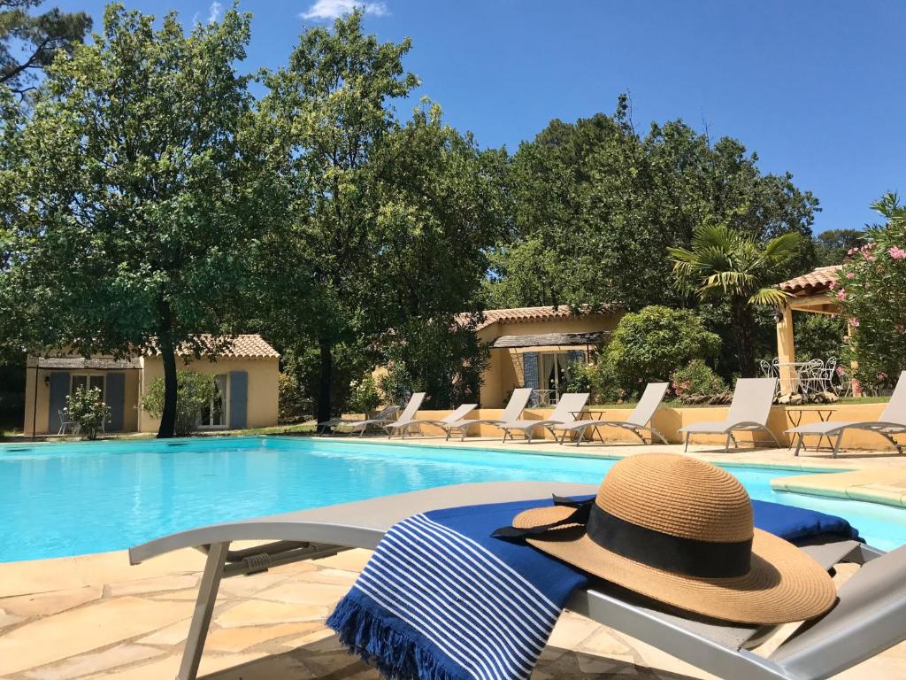 um chapéu sentado numa cadeira ao lado de uma piscina em Le Clos des Cigales em Roussillon