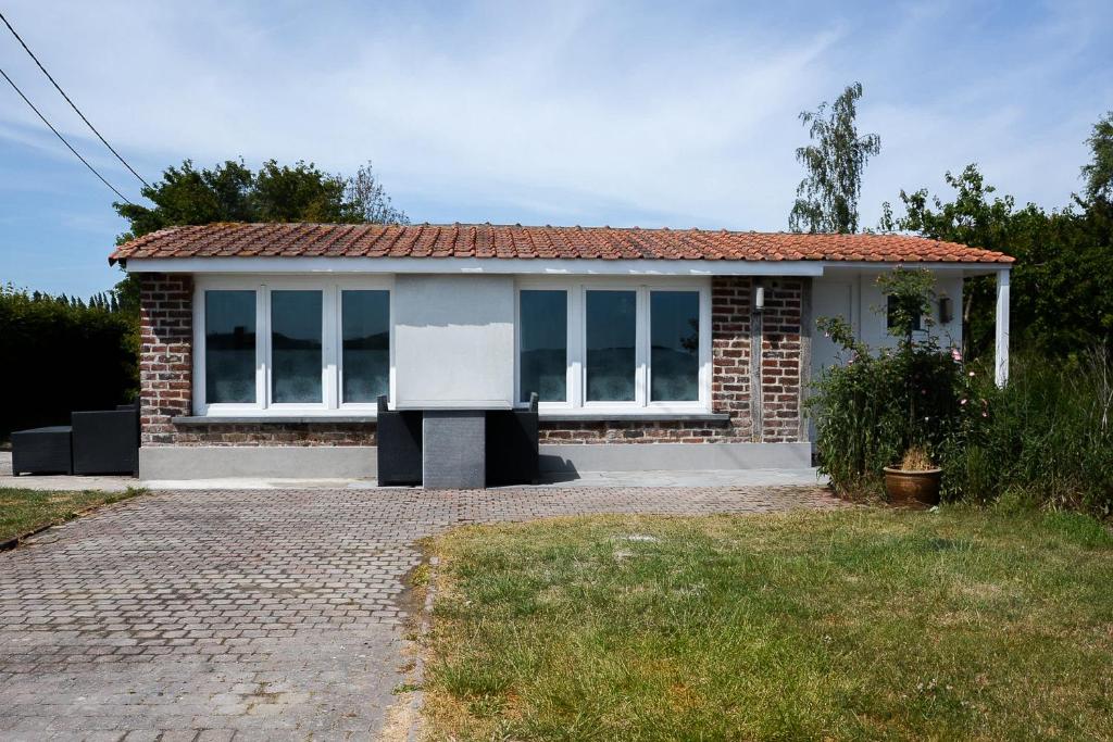 una pequeña casa de ladrillo con muchas ventanas en Chalet Den Keibilk en Heuvelland