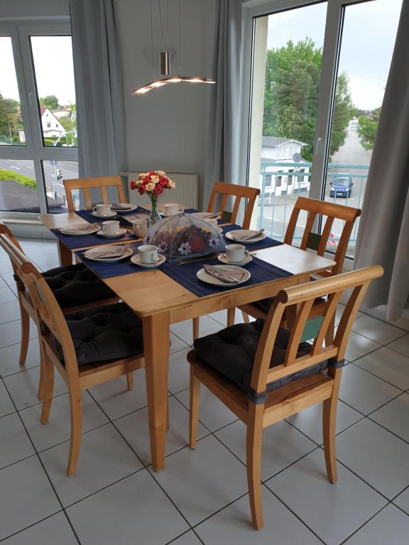 a wooden dining room table with four chairs and a table at Ferienwohnung Sonnenblick mit 3 Zimmer und Balkon in Zempin