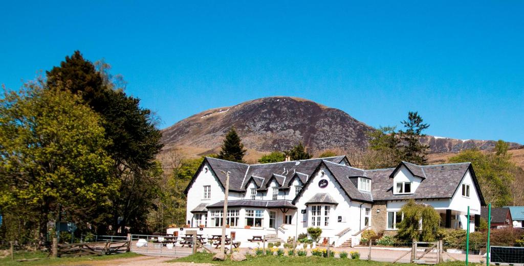 uma grande casa branca com uma montanha ao fundo em Glen Clova Hotel & Luxury Lodges em Millton of Clova