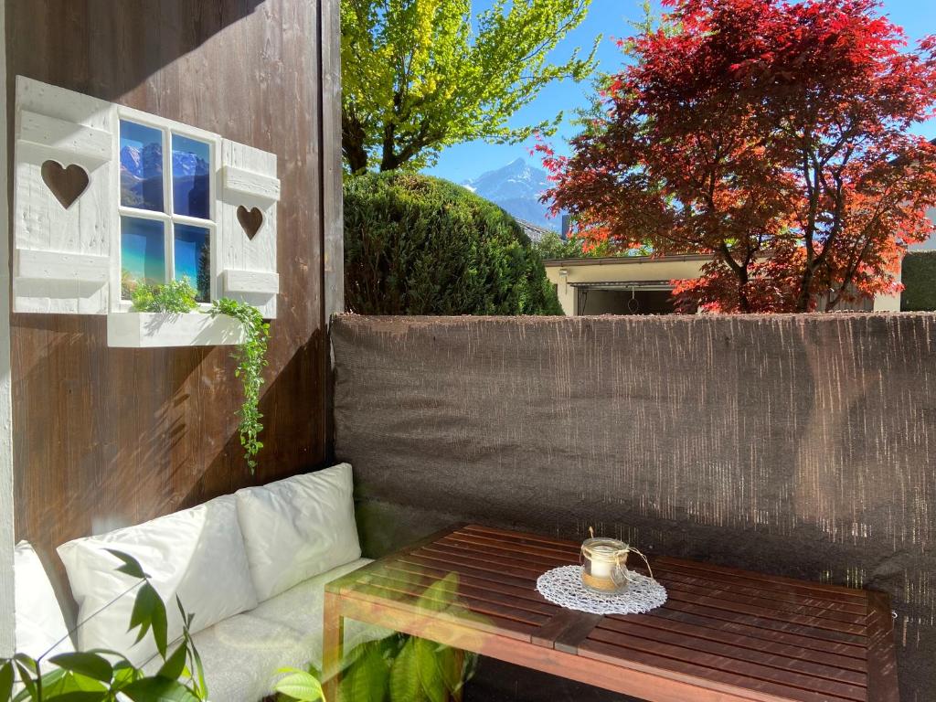 a patio with a table and a bench and a window at Puppi' s Nest mit Alpspitzblick in Garmisch- Partenkirchen in Garmisch-Partenkirchen