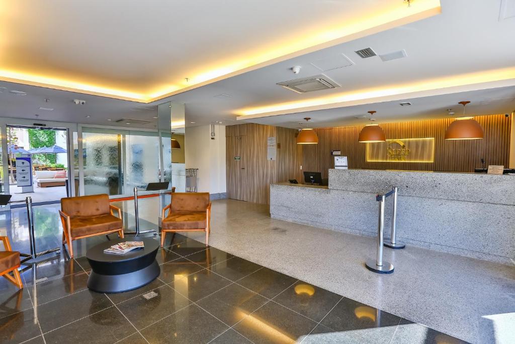 a lobby of a hotel with chairs and a counter at Sleep Inn Aeroporto de Guarulhos - São Paulo in Guarulhos