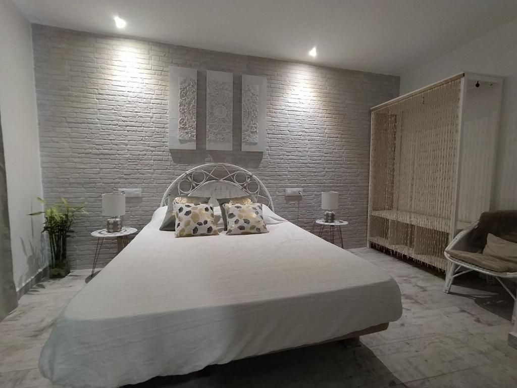 a bedroom with a large white bed and two chairs at Apartamento Laura in Peniscola