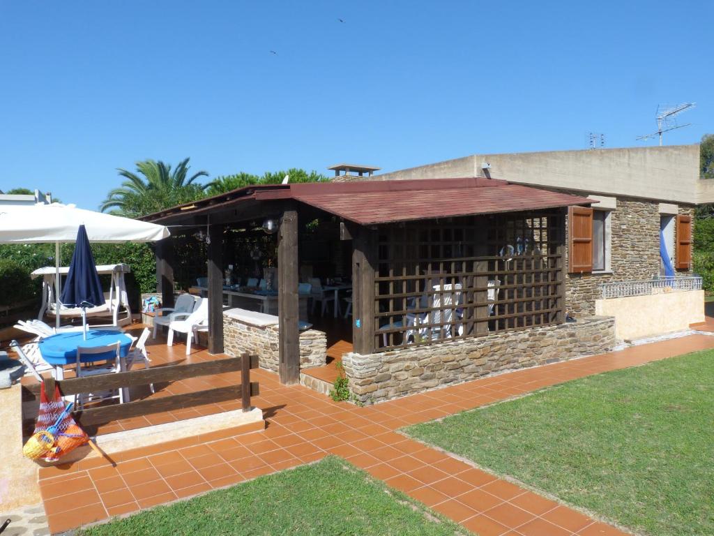een patio met een paviljoen met een tafel en stoelen bij Villetta La Ginestra in Stintino