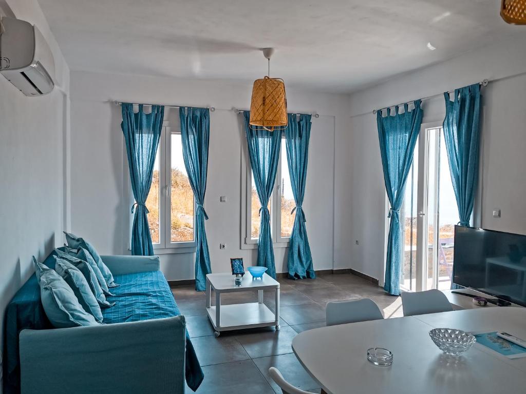 a living room with a blue couch and a table at Αλός αήρ suites in Kithnos