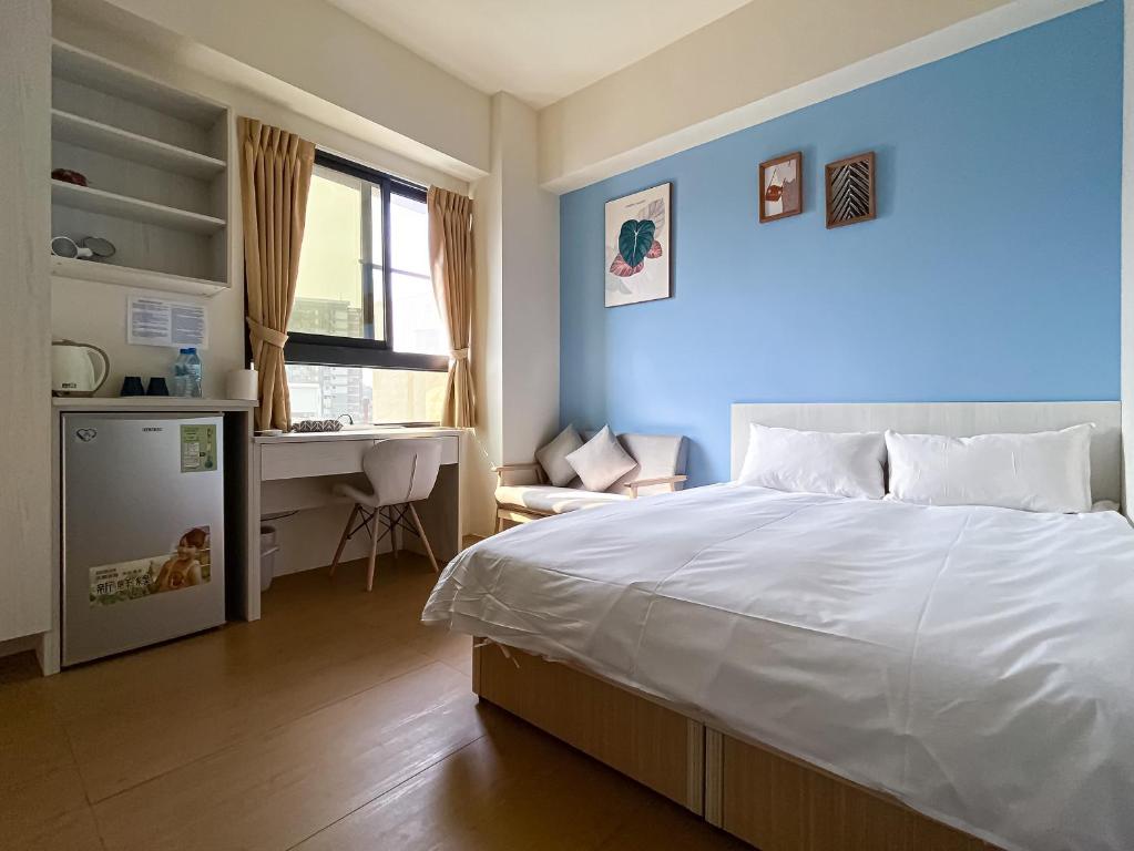 um quarto com uma cama branca e uma secretária em Adagio Hostel em Taichung