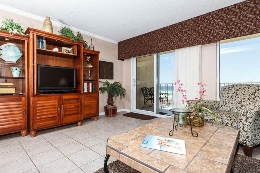 ein Wohnzimmer mit einem TV, einem Sofa und einem Tisch in der Unterkunft Island Echos 2nd - 3rd Floor Condos in Fort Walton Beach