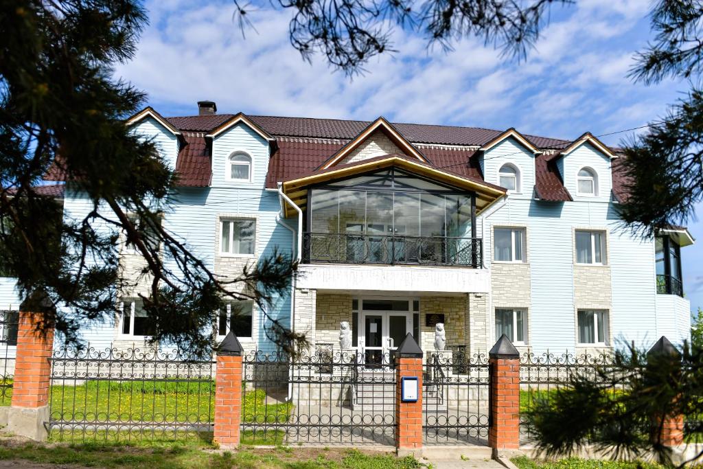 une grande maison blanche avec une clôture dans l'établissement Отель "Белокуриха", à Belokurikha